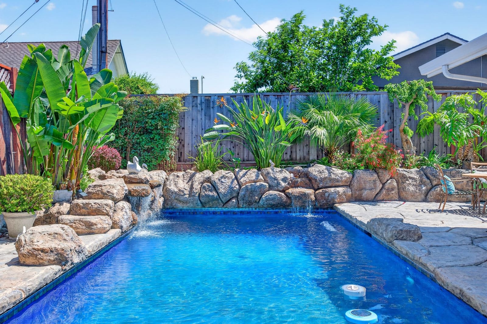 Resort-style black-bottom pool with waterfalls and tropical landscaping